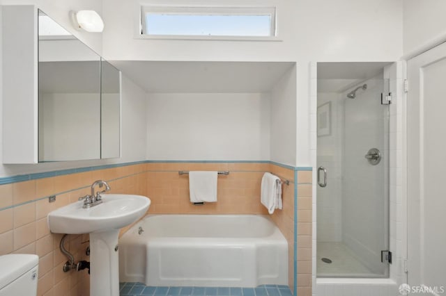 bathroom with separate shower and tub, tile walls, and toilet