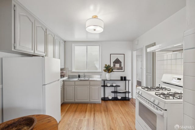 kitchen featuring sink, white appliances, and light wood-type flooring