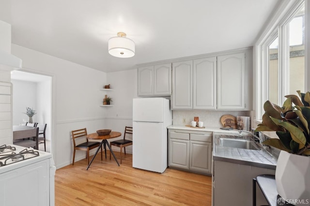 kitchen featuring sink, white appliances, light hardwood / wood-style flooring, gray cabinets, and decorative backsplash