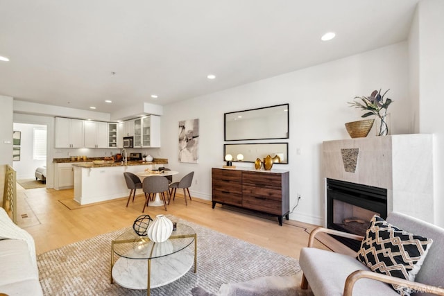 living area with light wood-style flooring, a tile fireplace, baseboards, and recessed lighting