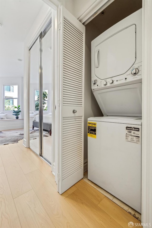 washroom featuring laundry area, light wood finished floors, and stacked washer and clothes dryer