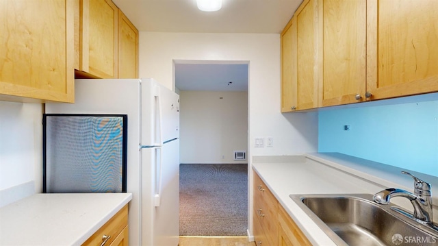 kitchen with carpet, sink, light brown cabinets, and white fridge