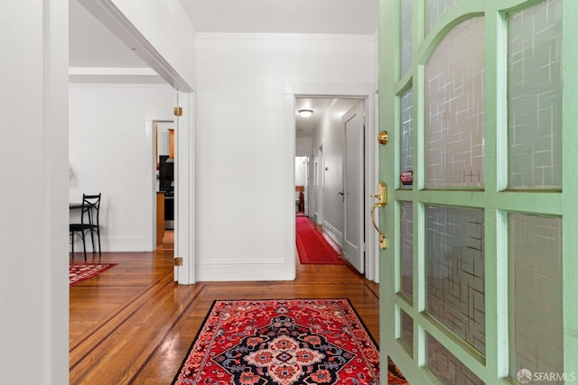 hall with baseboards, ornamental molding, and wood finished floors