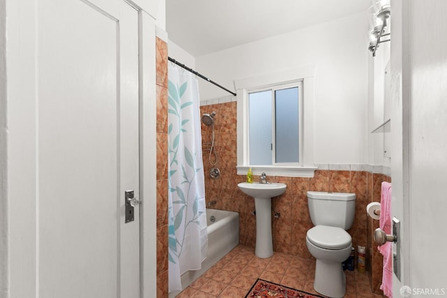 bathroom with a wainscoted wall, tile walls, shower / bathtub combination with curtain, toilet, and tile patterned flooring