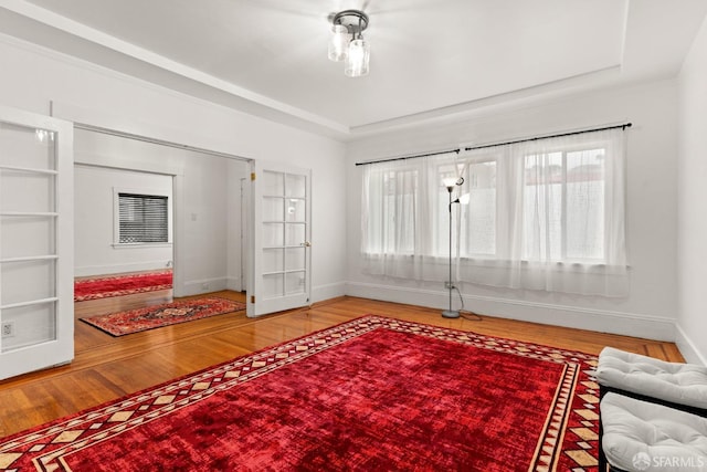 sitting room featuring baseboards, a tray ceiling, and wood finished floors