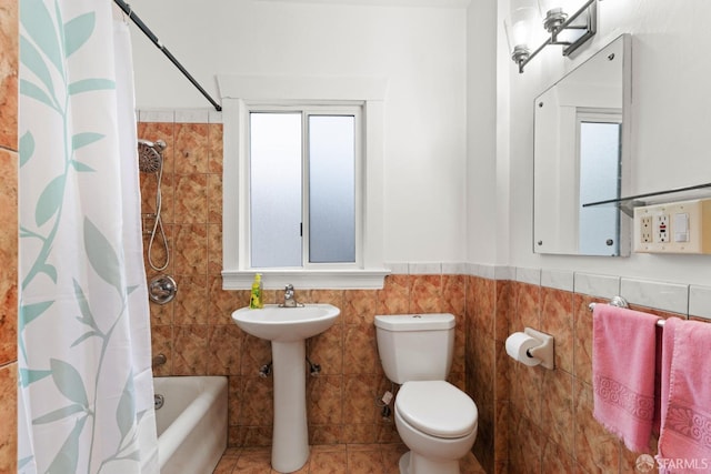 bathroom with toilet, shower / tub combo, tile walls, and wainscoting