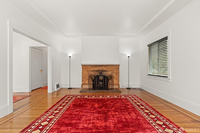 unfurnished living room featuring visible vents, a fireplace, baseboards, and wood finished floors