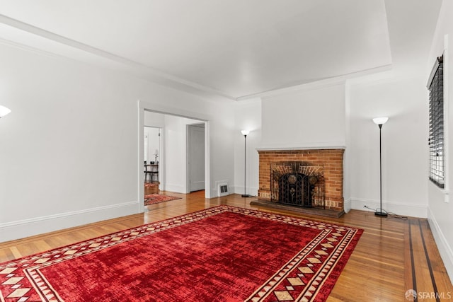 living room with visible vents, a fireplace, baseboards, and wood finished floors