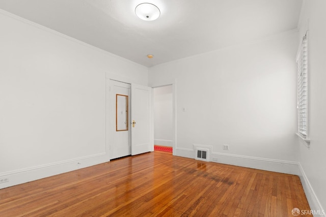 unfurnished room with baseboards, visible vents, and hardwood / wood-style floors