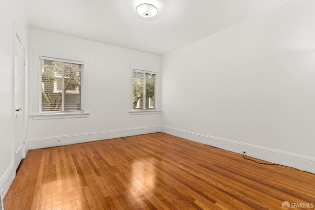 spare room with a healthy amount of sunlight, baseboards, and hardwood / wood-style flooring