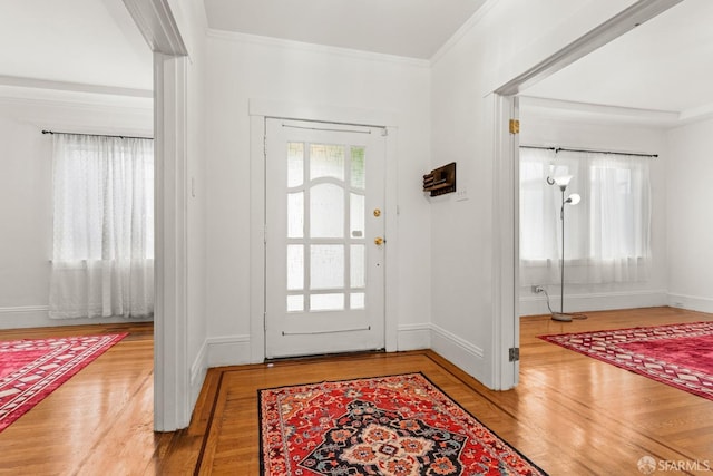 foyer entrance with plenty of natural light, wood finished floors, and crown molding