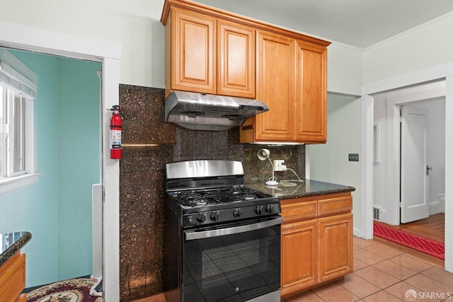 kitchen with decorative backsplash, ornamental molding, black range with gas stovetop, under cabinet range hood, and light tile patterned flooring