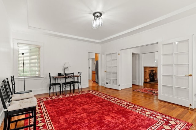 sitting room with a tray ceiling, baseboards, and wood finished floors