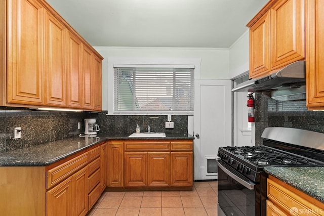 kitchen with light tile patterned flooring, black gas range, under cabinet range hood, a sink, and backsplash