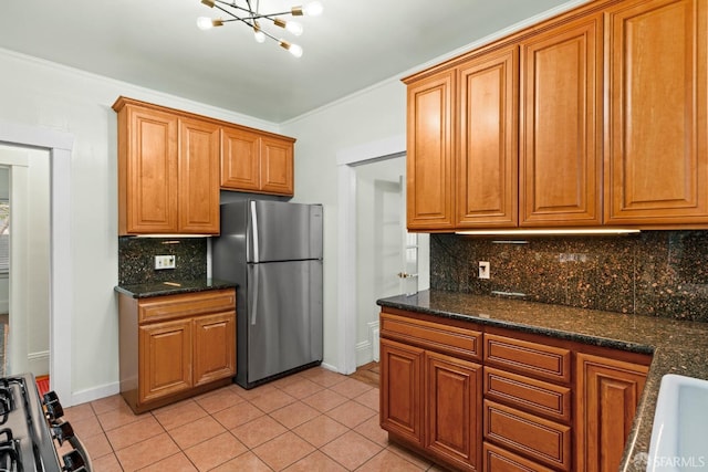 kitchen with tasteful backsplash, brown cabinetry, light tile patterned flooring, and freestanding refrigerator