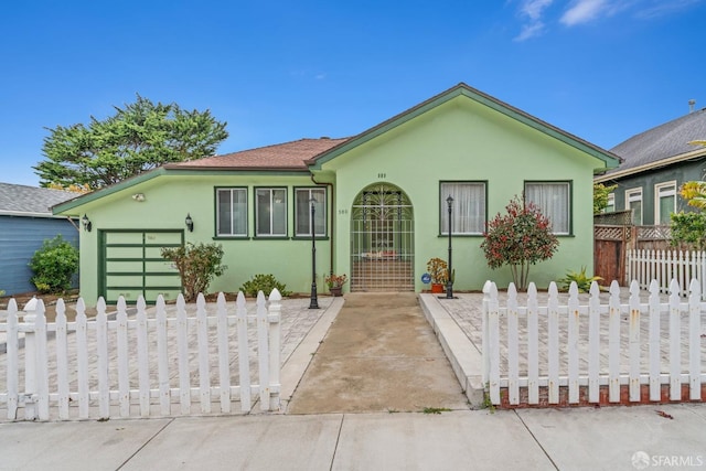 single story home featuring a garage, concrete driveway, a fenced front yard, and stucco siding