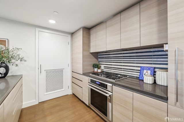 kitchen with decorative backsplash, stainless steel appliances, and light hardwood / wood-style floors