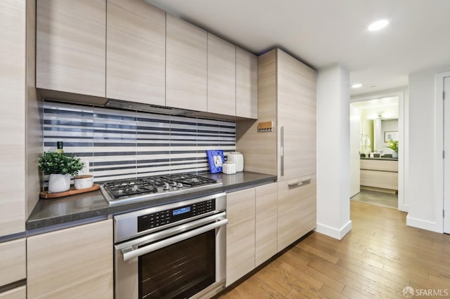 kitchen featuring light hardwood / wood-style flooring, stainless steel appliances, backsplash, and light brown cabinets