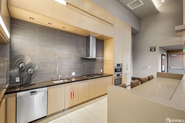 kitchen with sink, light tile patterned flooring, wall chimney range hood, stainless steel appliances, and tasteful backsplash