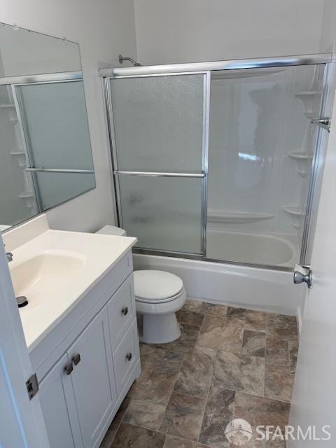 full bath featuring vanity, toilet, bath / shower combo with glass door, and stone finish flooring