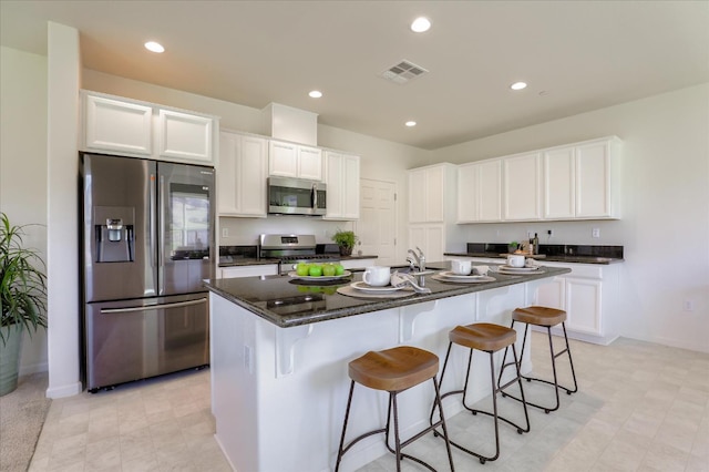 21051 Pinot Noir Dr, Patterson, CA 95363 - kitchen with stainless steel appliances, white cabinetry, a center island with sink, a breakfast bar area, and recessed lighting