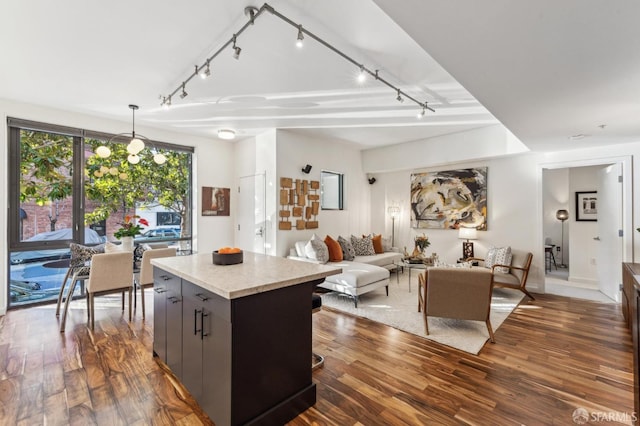 kitchen with an inviting chandelier, gray cabinets, decorative light fixtures, a kitchen island, and dark hardwood / wood-style flooring