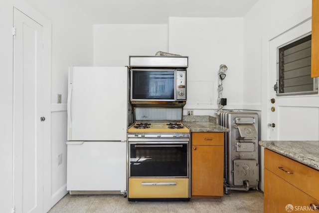 1915 Laguna St Unit 4, San Francisco, CA 94115 - kitchen featuring black microwave, light stone countertops, brown cabinets, freestanding refrigerator, and range with gas stovetop