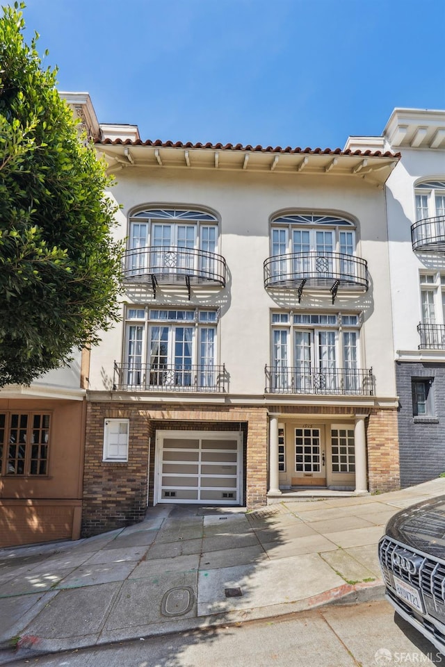 1915 Laguna St Unit 4, San Francisco, CA 94115 - view of front of property with brick siding, a balcony, concrete driveway, an attached garage, and stucco siding