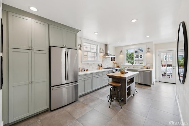 57 Theresa St, San Francisco, CA 94112 - kitchen featuring appliances with stainless steel finishes, wall chimney exhaust hood, decorative backsplash, recessed lighting, and a kitchen island