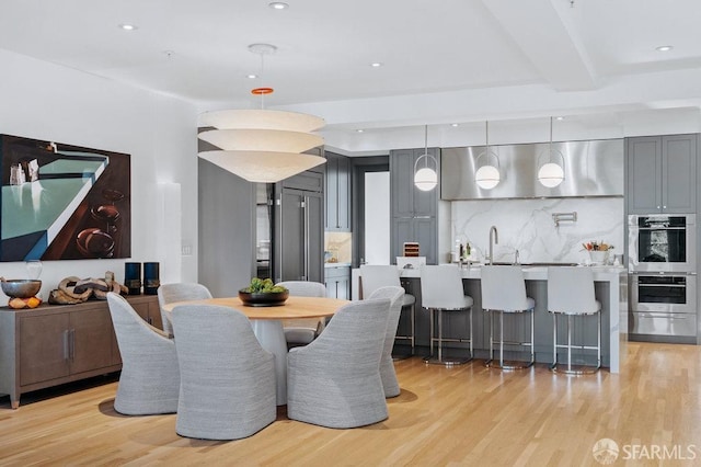 dining room featuring beam ceiling and light wood-type flooring