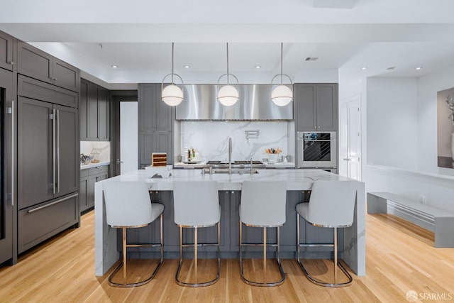 kitchen featuring gray cabinetry, pendant lighting, stainless steel appliances, and an island with sink