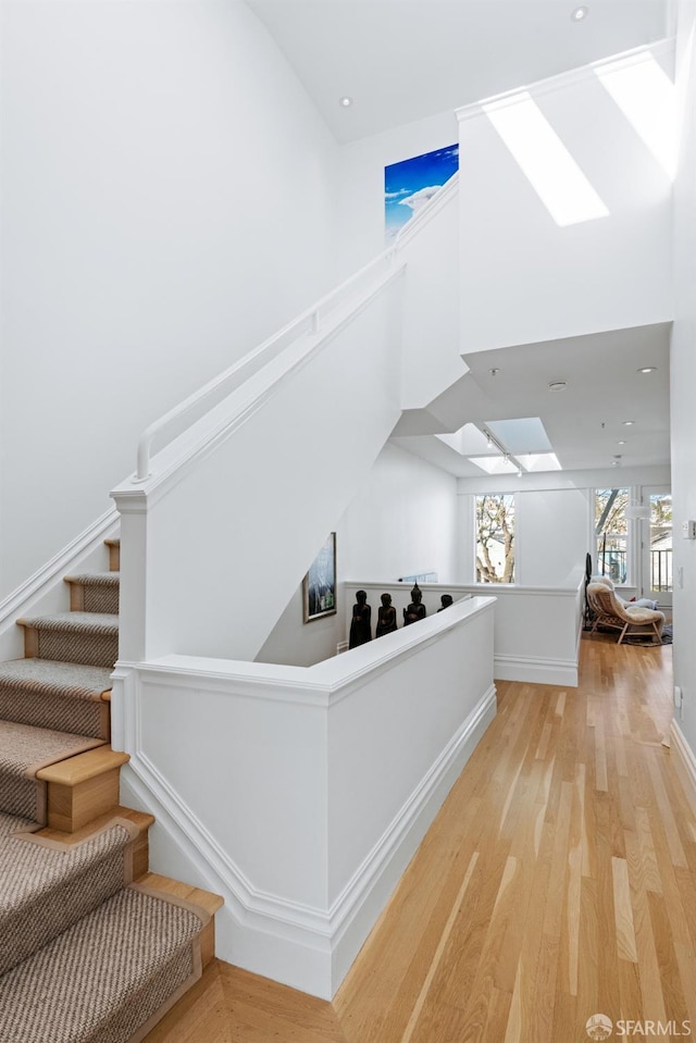 interior space with a skylight, a high ceiling, and light wood-type flooring