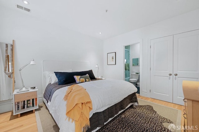 bedroom featuring ensuite bath, light hardwood / wood-style flooring, and a closet