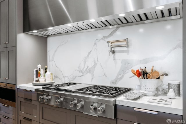 kitchen with backsplash, stainless steel gas stovetop, and exhaust hood