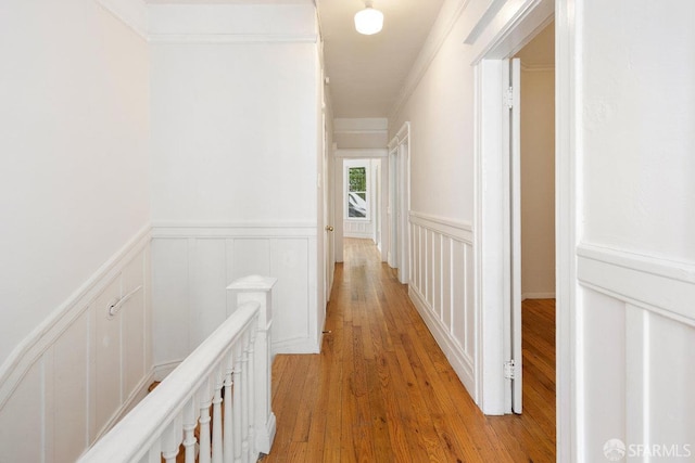 corridor with light hardwood / wood-style flooring and crown molding