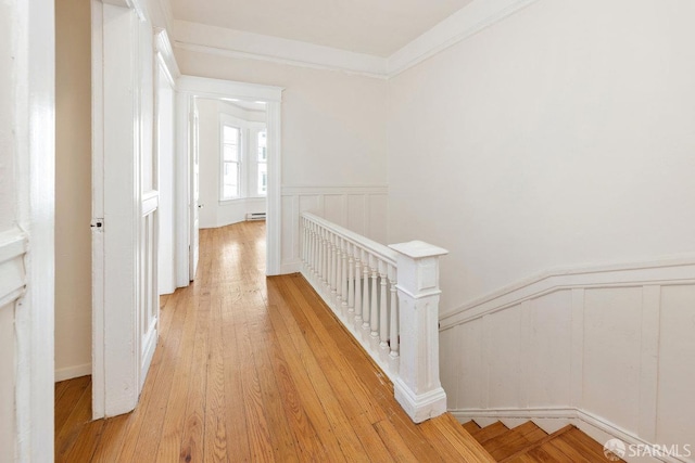 hallway with light wood-type flooring and ornamental molding