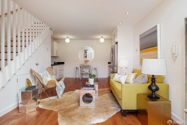 living area with stairs, wood finished floors, and baseboards