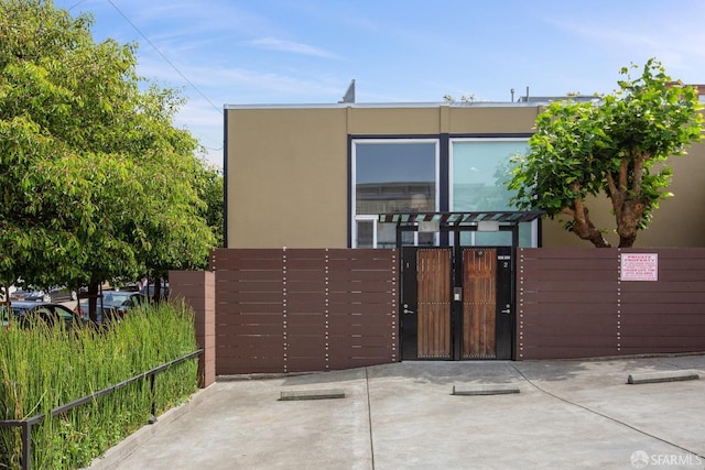 view of front of property featuring fence, a gate, and stucco siding