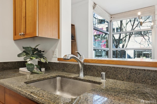 room details featuring stone counters, a sink, and brown cabinets