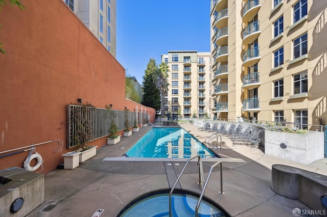 community pool with a community hot tub, a patio, and fence