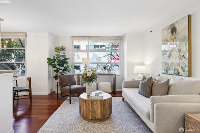 living room with a healthy amount of sunlight, dark wood-style floors, baseboards, and ornamental molding