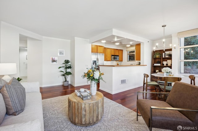 living room featuring an inviting chandelier, baseboards, visible vents, and dark wood finished floors