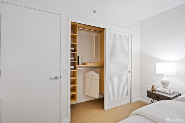 bedroom featuring baseboards, a closet, and light colored carpet