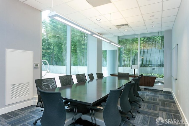 carpeted dining room with visible vents, a paneled ceiling, a wall of windows, and baseboards