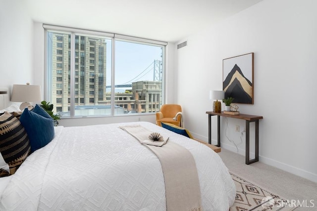 bedroom featuring visible vents, baseboards, carpet floors, and a view of city