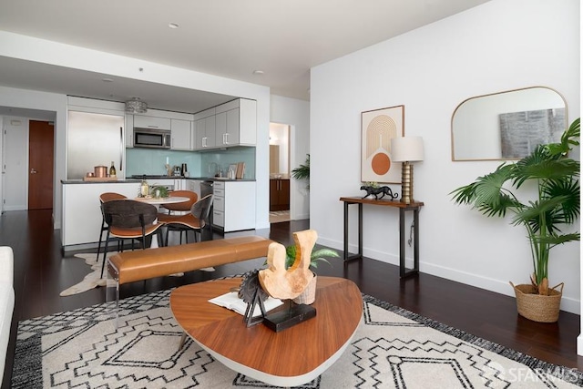 living area featuring indoor wet bar, baseboards, and wood finished floors