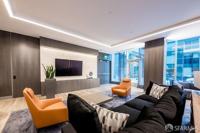 living room featuring wood walls, a wall of windows, a tray ceiling, and wood finished floors