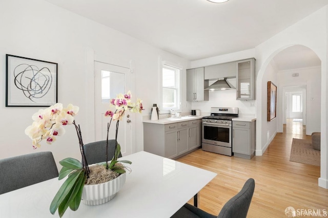 24 Magnolia St, San Francisco, CA 94123 - kitchen featuring gas stove, gray cabinets, wall chimney exhaust hood, arched walkways, and healthy amount of natural light