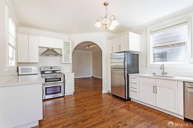 24 Magnolia St, San Francisco, CA 94123 - kitchen featuring stainless steel appliances, a sink, wall chimney range hood, arched walkways, and a chandelier