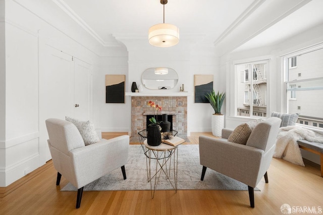 living area with ornamental molding, a tiled fireplace, and wood finished floors